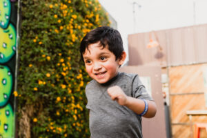 Little boy is running towards viewer wearing a Pal Experiences bracelet